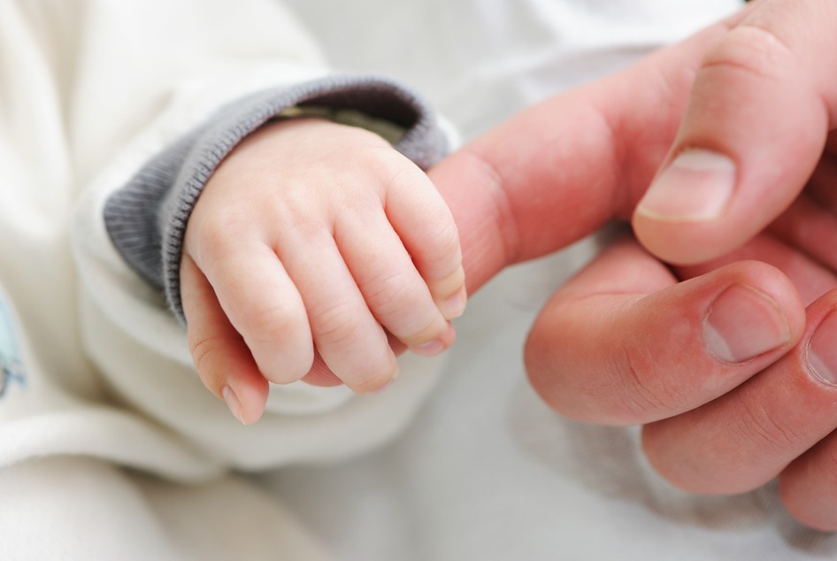 Newborn baby holding father's finger